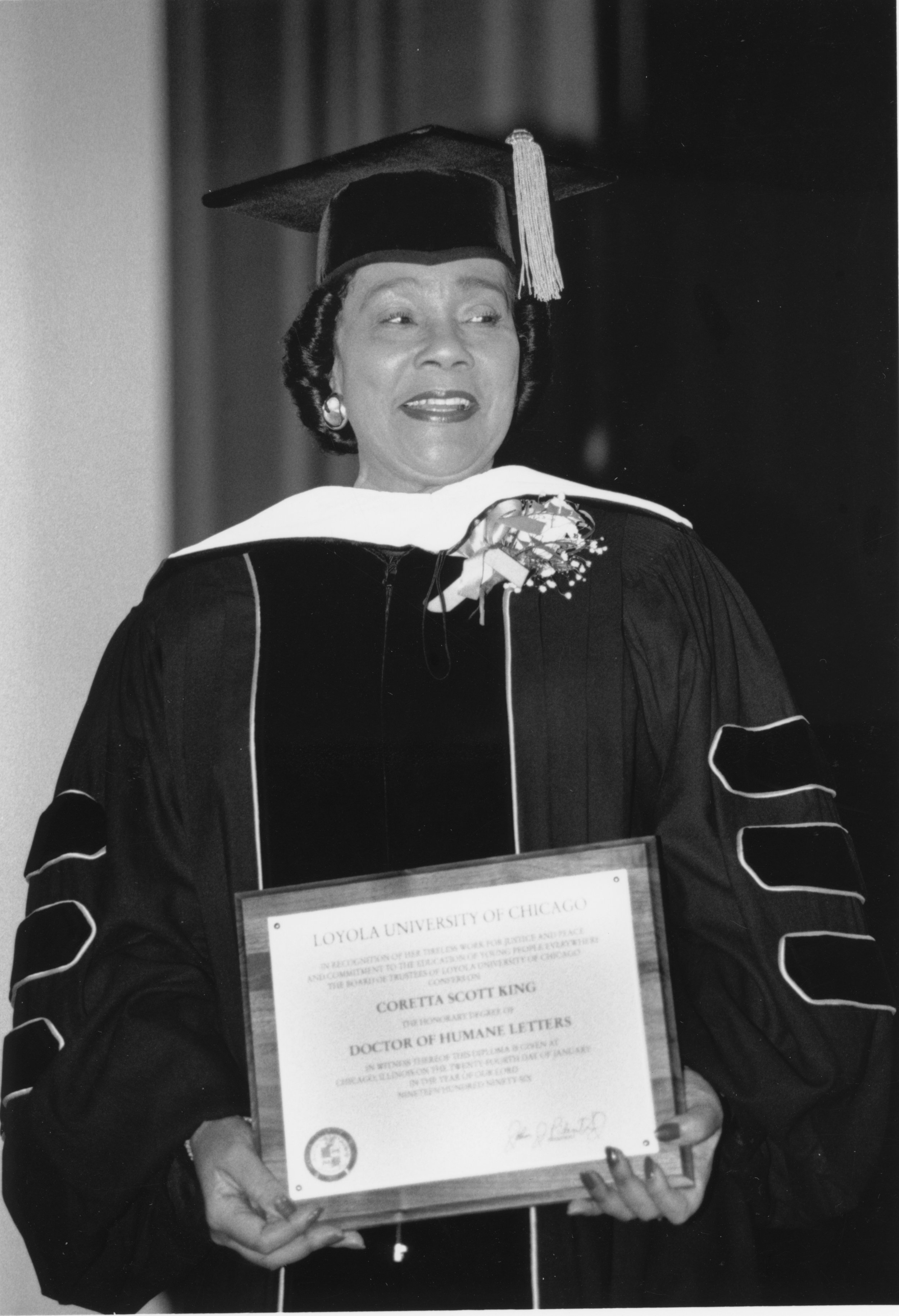 A woman, Coretta Scott King, in graduation gear carrying an award by Loyola